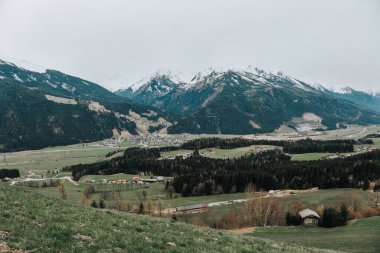 Dağ manzarası manzarası, gri bulutlu dağlar. Karlı Dağlar ve Yeşil Vadi manzarası. Dağlarla çevrili Alp Köyü manzarası.. 