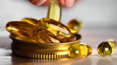 Arka planda sarı omega kapsüller var. Sağlıklı yağ ve beslenme. Omega asit jelatin kapsülleri. 4k görüntü