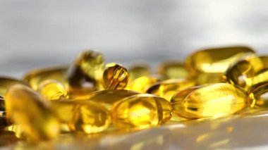 Balık yağı kapsülleri masaya düşer. Sağlıklı yağ ve besin maddeleri. Jöle kapsüllerinde Omega yağ asitleri. 4k görüntü