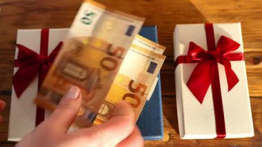 Hediye almanın maliyeti. Avro banknotları hediye kutularına düşer. Bayram hediyeleri için zıplarlar. Tatil için hediyeler alıyorum. 4k görüntü