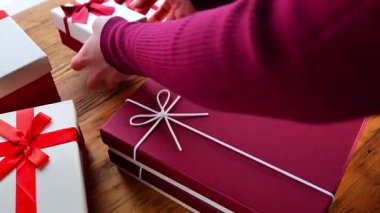 Tatil hediyeleri. Eller ahşap bir masa üzerinde hediye kutuları topluyor. Alma ve hediye verme süreci. Anneler günü, doğum günü, Noel hediyeleri ve sürprizler. 4k görüntü