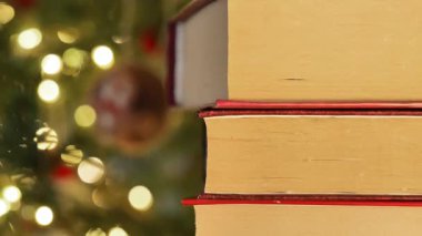 Noel ve kış tatilleriyle ilgili kitaplar. Kırmızı kaplı kitaplar Noel ağacının arka planına istiflenir. Kış atmosferik tatil kitapları. 4k görüntü