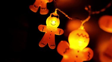 Zencefilli çörekler siyah arka planda kürek çeker. Karanlıkta parlayan Noel çelengi. Sıcak, hafif bir Noel çelengi. 4k görüntü