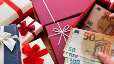 Para hediyesi. Eller avroluk parayı fiyonklu bir hediye kutusuna koydu. Tatil için para sürprizi. 4k görüntü
