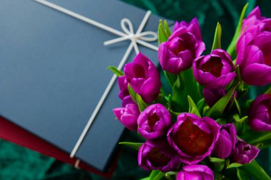 Mor Çiçek Buketi ile sarılmış bir hediye. Kurdele Üst Görünümlü Paketlenmiş Hediyeler. 