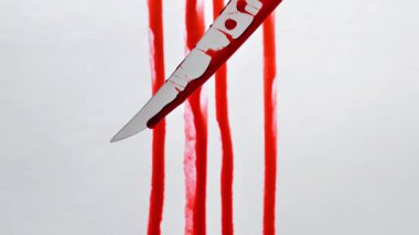 Soğuk silah saldırısı. Bıçaktan damlayan kan damlaları kan lekeli beyaz bir duvara damlıyor. Suç mahalli ve cinayet kavramı. 4k görüntü