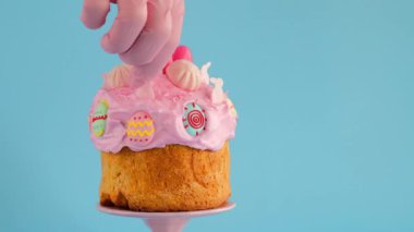 Paskalya pastası. Paskalya pastası dekorasyonu süreci. El, paskalya pastasını, pastel pembe tonlarda şekerli süslemelerle süslüyor. 4k görüntü