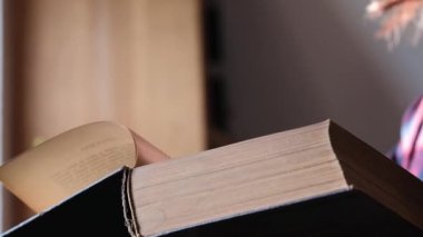 Kitap ellerde. Parmaklar karanlık odada kitabın sayfalarını çeviriyor. Okuma ve bilgi. 4k görüntü