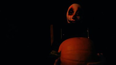 Karanlıkta ellerinde balkabağı olan kanlı bir maske. Cadılar Bayramı tatili. Kanlı Balkabağı Canavarı