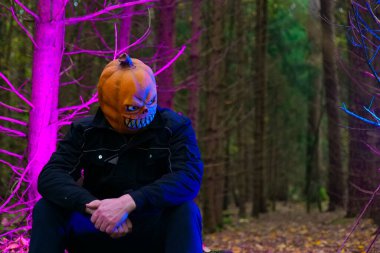 Gece Ormanındaki Balkabağı Maskeli Adam. Karanlık Ormanda Oturan Balkabağı Kafa.. 