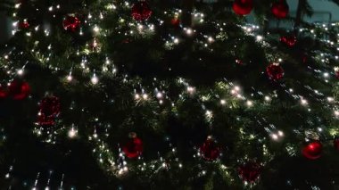 Topları ve çelenkleri olan Noel ağacı. Köknar ağaçlarının dallarında parlayan Noel çelenkleri. Avrupa 'da kış tatili. 4k görüntü