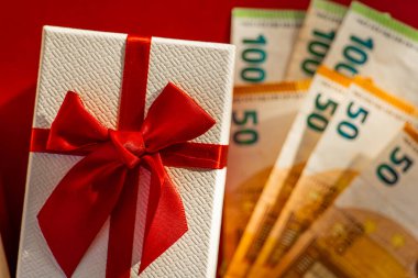 Avrupa Banknotları ile Hediye Kutusu. Kırmızı Arkaplanda Hediye ve Euro Para Birimi. Kırmızı Hediye Kutularının Üzerinde Euro Banknotları. Kırmızı Paketli Hediyenin Yanında Nakit Hediye. Hediye almanın maliyeti. 