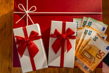 Avrupa Banknotları ile Hediye Kutusu. Kırmızı Arkaplanda Hediye ve Euro Para Birimi. Kırmızı Hediye Kutularının Üzerinde Euro Banknotları. Kırmızı Paketli Hediyenin Yanında Nakit Hediye. Hediye almanın maliyeti. 