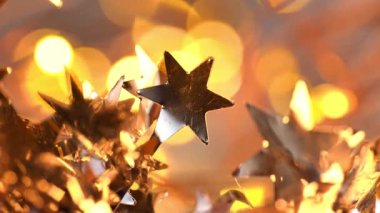 Altın ve gümüş tonlarda ışıldayan şenlikli bir arka plan. Yıldızlarla süslenmiş gümüş süsler ve yanıp sönen altın bokeh. Yeni yıl ve Noel duvar kâğıdı. 4k görüntü