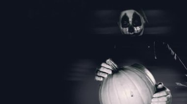 Cadılar Bayramı atmosferi. Karanlıkta büyük bir balkabağı olan korkunç maske karakteri. Karanlıkta siyah beyaz korkunç bir portre. 4k görüntü