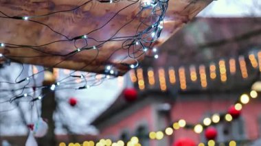 Avrupa 'da Noel zamanı. Çelenkler ve kışın ağaçlarda kırmızı toplar. Arka planda evler. 4k görüntü