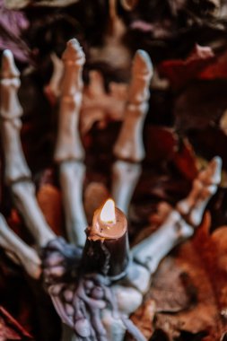 Cadılar Bayramı şamdanı. Sonbahar havası. Sonbahar Yaprakları 'nda İskelet El Tutma Mumu. Cadılar Bayramı mumları. Sonbahar Yaprakları ile İskelet El' de Yanan Mum..