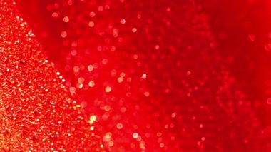 Kırmızı parlak kumaş arka plan. Noel ve Yeni Yıl arkaplanı. Işıltılı makro fon, parlak bokeh. Yanardöner doku. Kırmızı tonlarda parlak kumaş kıvrımları. 4k görüntü