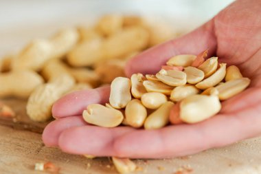 Tahta Yüzeyde Fıstıklar Elde. Yakın plan El Tutma Kabuklu Fıstık. Sağlıklı atıştırmalık. Fıstık ezmesi malzemesi.