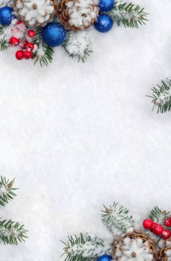 Christmas decoration. Cone pine, branches christmas tree, blue ball, red berries on snow with space for text. Top view, flat lay