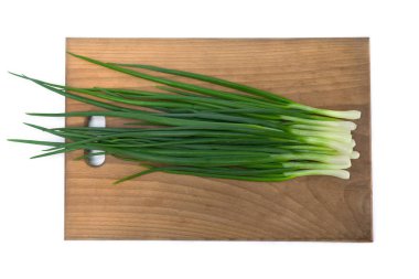 Fresh green onions on wooden cutting board on white background. Top view, flat lay