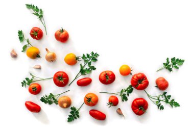 Kırmızı ve sarı domatesler, çeşitli renklerde taze domatesler ve tarla mahsulü, maydanoz, soğan, sarımsak beyaz arka planda yazı için yer var. Üst manzara, düz uzanma