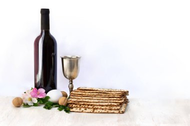 Matzo, şarap, gümüş kase, pembe çiçekler elma ağacı, beyaz yumurta ve cevizler Hamursuz Bayramı kutlaması için beyaz ahşap masa üzerinde açık arkaplanda mesaj için yer var.