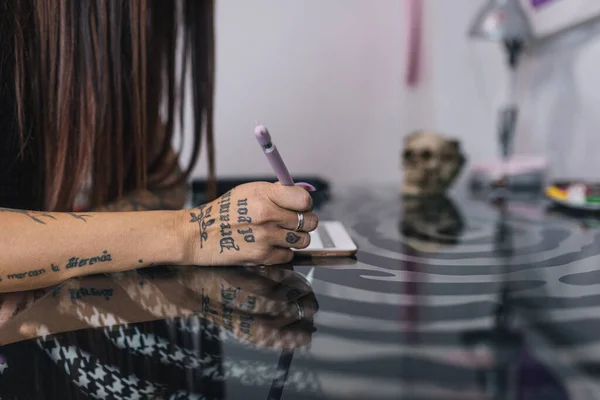 Tattoo artist hands designing a tattoo on her tablet.