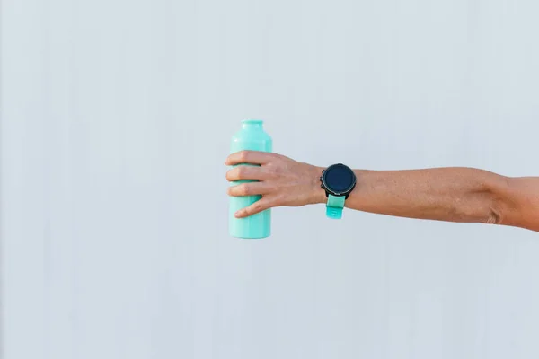 Arm with a water bottle and a sports smart watch.