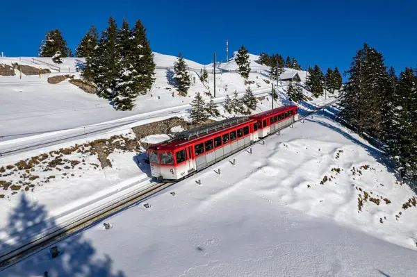 Kızıl Rigibahn treni kış mevsiminde Vitznau yolunda Rigi Dağı 'ndan inerken görülüyor.