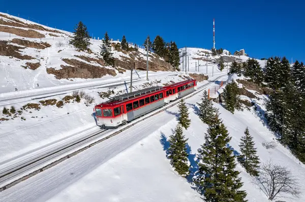 Kızıl Rigibahn treni kış mevsiminde Vitznau yolunda Rigi Dağı 'ndan inerken görülüyor.