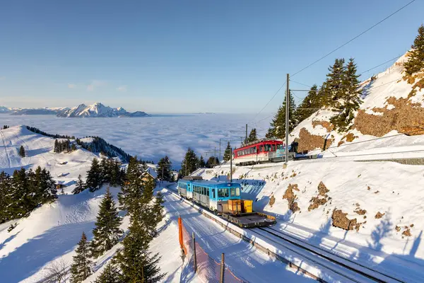 Güneşli bir kış sabahı, Rigi Dağı 'nın zirvesine yaklaşan iki tren var..