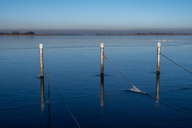 Kışın boş rıhtım manzarası. Mavi su ve açık mavi gökyüzü
