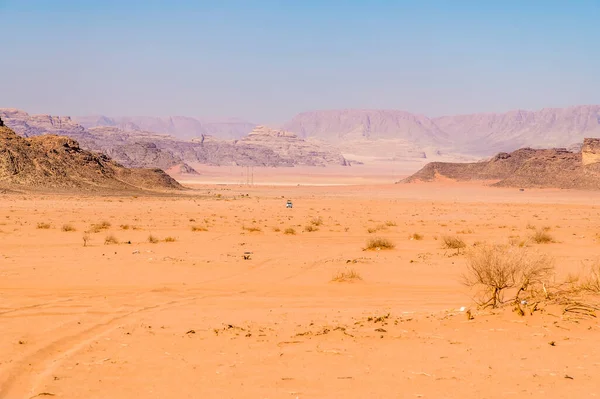 stock image A view of a lone vehicle in the vast sandy and rocky landscape in Wadi Rum, Jordan in summertime