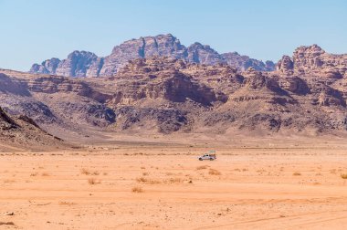 Yazın Ürdün 'ün Wadi Rum şehrinde kayalık zemini olan yalnız bir aracın görüntüsü
