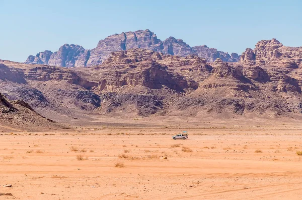 Yazın Ürdün 'ün Wadi Rum şehrinde kayalık zemini olan yalnız bir aracın görüntüsü