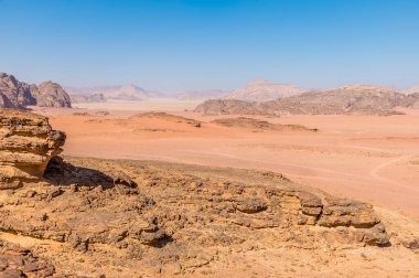 Yazın Ürdün 'ün Wadi Rum kentindeki uçsuz bucaksız çöl arazisinde kayalık çıkıntıları aşan bir manzara