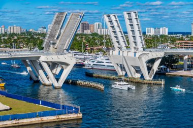 A close up view of boats sailing through the bridge across the Stranahan River from Port Everglades, Fort Lauderdale on a bright sunny day