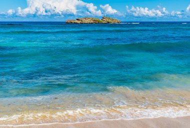 A view along the shore from a beach in Puerto Plata in the Dominion Republic on a bright sunny day