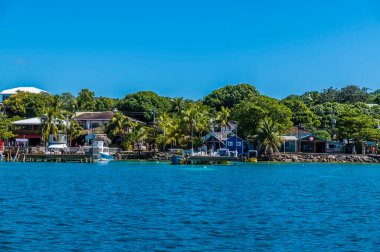 Güneşli bir günde Roatan Adası 'ndaki Batı Körfezi' ndeki tekne ve binaların manzarası