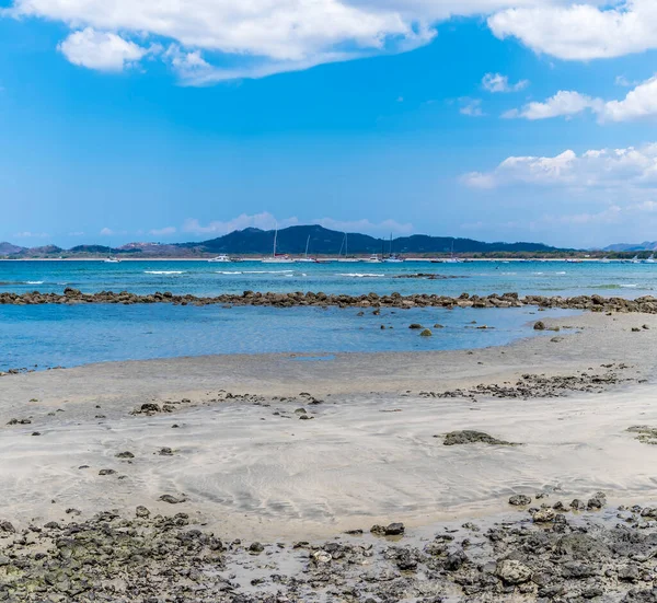 乾燥した季節にコスタリカのTamarindoの湾を渡ってビーチと岩の防波堤の上の景色 — ストック写真