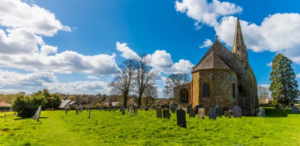 A view across the churchyard of the Anglo Saxon church in the village of Brixworth, Northamptonshire, UK in summertime