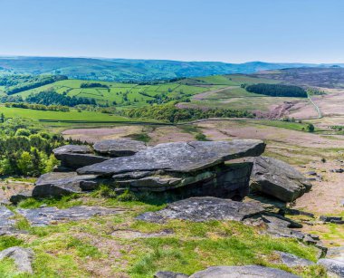 İngiltere 'nin Peak District bölgesindeki Stanage Edge yamacındaki kayalıkların tepesindeki değirmen taşı manzarası