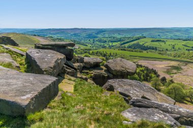 İngiltere 'nin Peak District bölgesindeki Stanage Edge yamacındaki kayalıkların tepesinde dengelenmiş değirmen taşı manzarası
