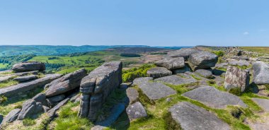 Stanage Edge yamacının tepesindeki değirmen taşlarının manzarası yaz mevsiminde İngiltere 'nin Peak District bölgesindeki vadiye doğru bakıyor.
