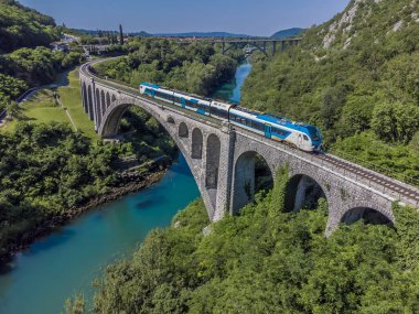 Slovenya 'nın Solkan kentinin dışındaki taş demiryolu köprüsünden geçen trenin havadan görüntüsü