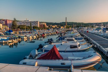 Slovenya 'nın Izola limanında yaz mevsiminde demirlemiş teknelerin gün batımında bir manzara