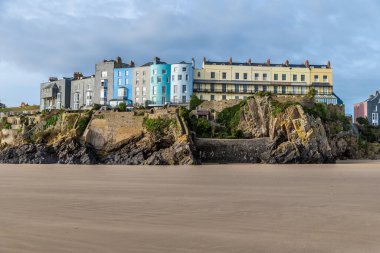 Güneşli bir günde, Galler, Tenby 'de Castle sahilinden kayalıklara ve renkli binalara doğru bir manzara.
