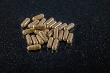 Siyah mermer tabakta Pygeum Africanum kapsüllerinin yakın görüntüsü