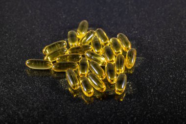 Koyu mermer tabakta morina yağı kapsüllerinin yakın görüntüsü.